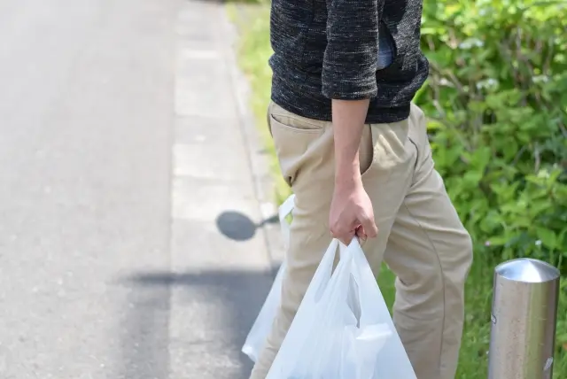 破れそうなレジ袋を持つ男性の画像